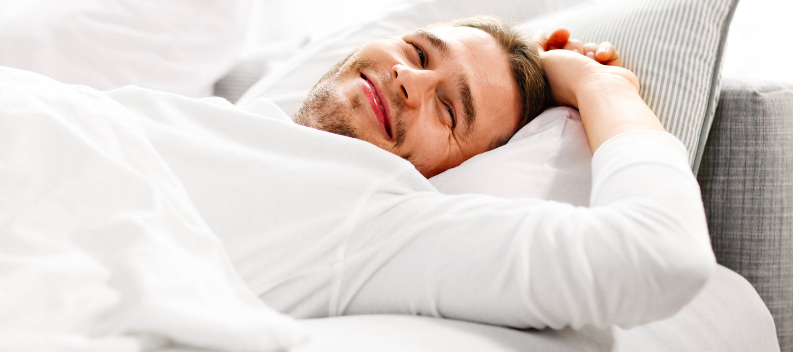 young man waking up smiling in his bed