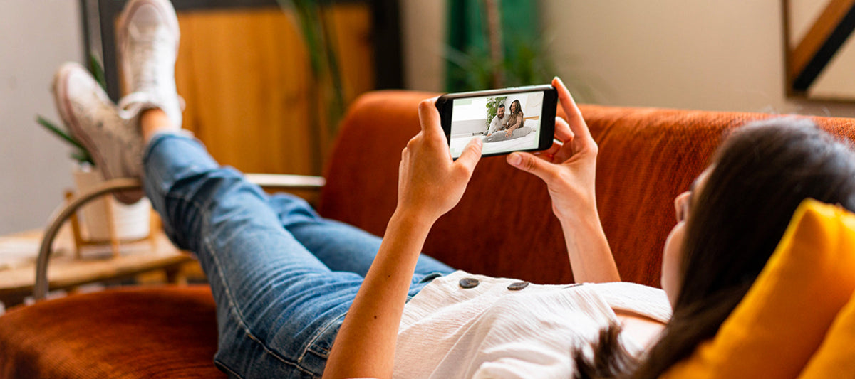 woman lying down on the couch watching her phone