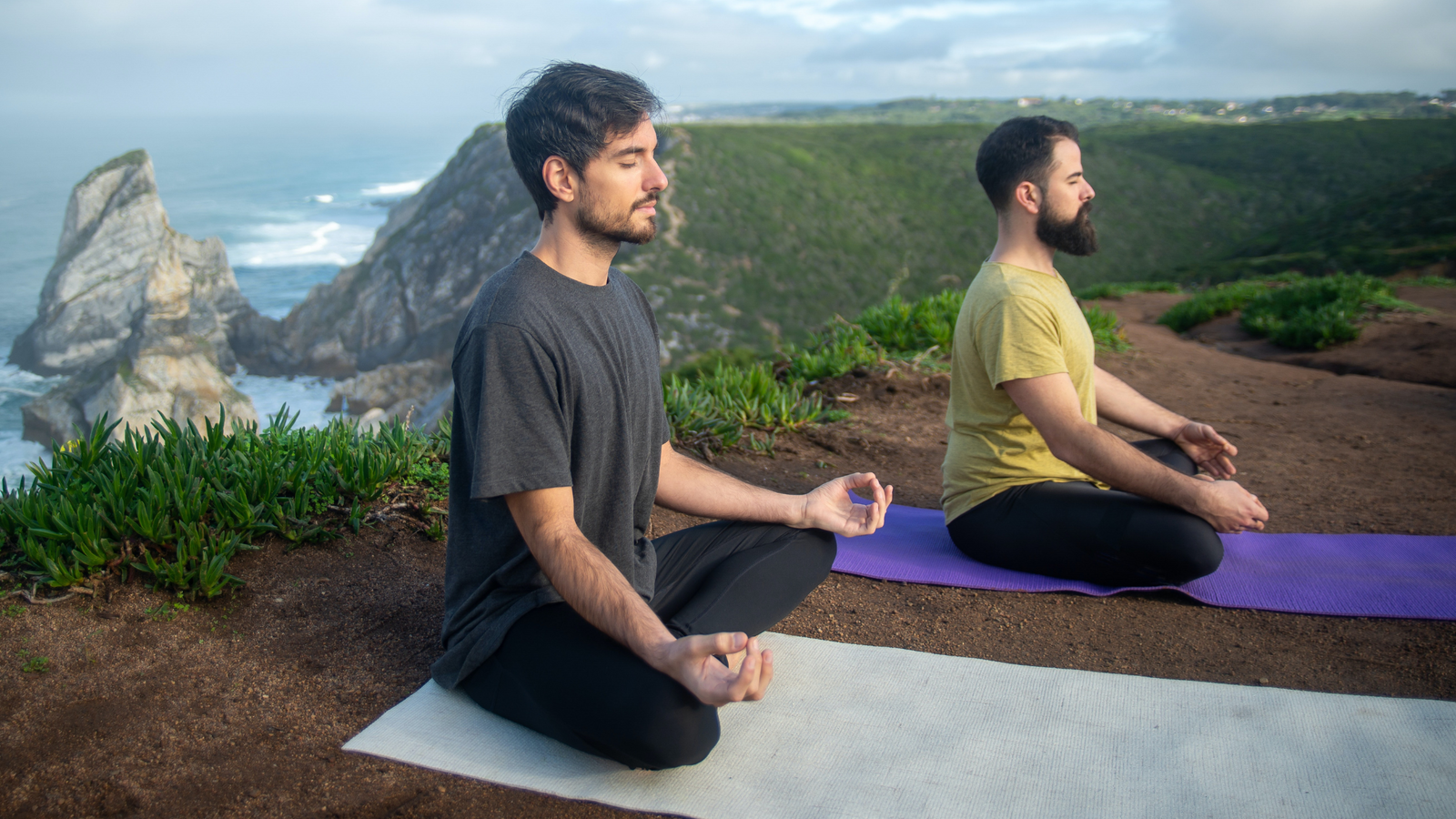 two mens practicing yoga on a mountain