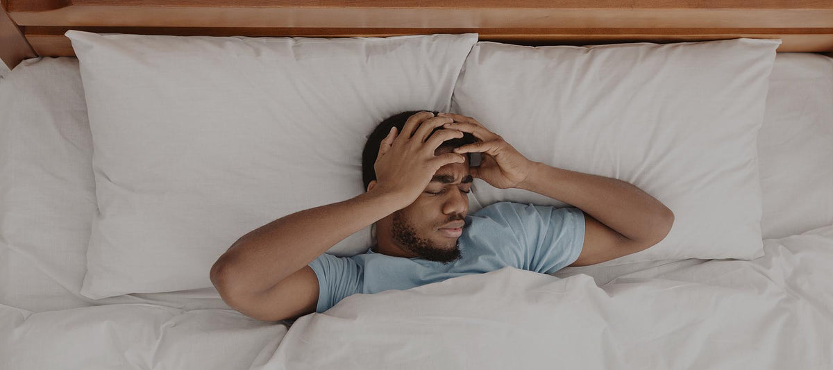 man in bed suffering from headache