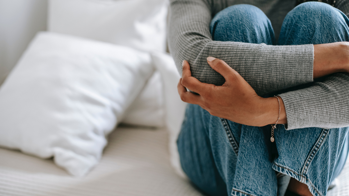 Woman suffering from chronic stress sitting on her bed